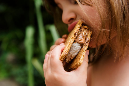 Girl taking big bite of a s'more