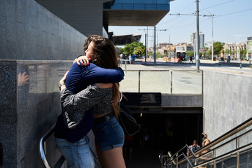 Couple hugging to say goodbye outside metro station.