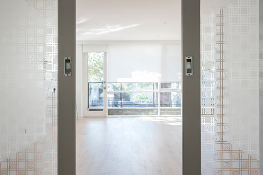 Glass panelled doors opening to a large empty apartment