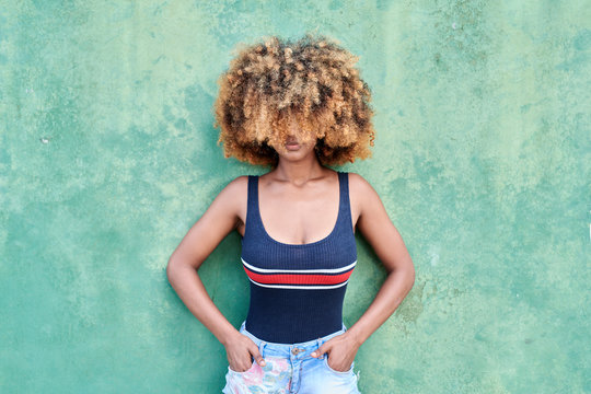 Woman covering her face with hair standing by wall