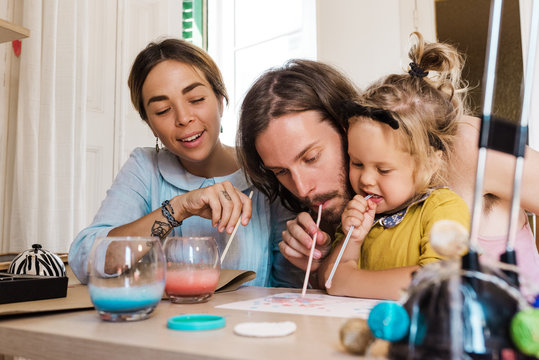 Playful girl with parents drawing with straws