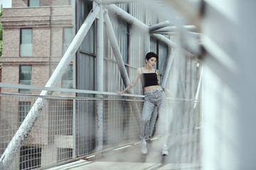 Raven haired young lady with tattoos posing on the bridge