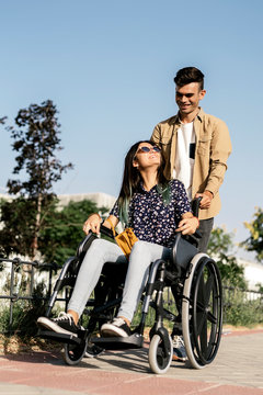 Young woman sitting on a wheelchair and her boyfriend walking