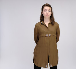 A portrait above the knee of a pretty adult brunette girl in a dress on a white background. Standing directly in front of the camera, showing different poses and emotions.