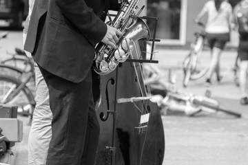 Street musician's hands playing saxophone and double-bass in an urban environment. Black and white...