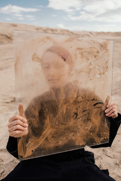 Anonymous person hiding behind dirty glass