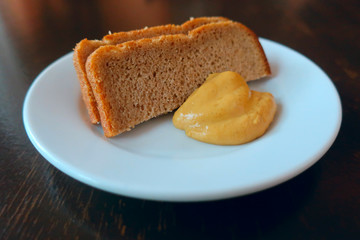 two slices of bread with mustard on a white platter