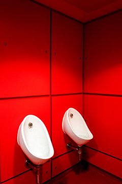 Urinals in a red bathroom
