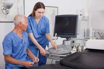 Skilled sonographer showing new equipment to assistant