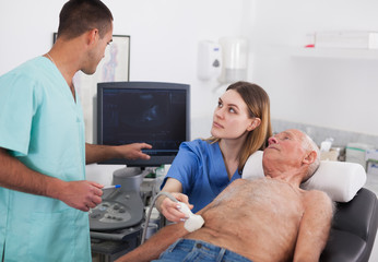 Woman and man doctors examines a senior man at abdomen