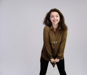 A portrait above the knee of a pretty adult brunette girl in a dress on a white background. Standing directly in front of the camera, showing different poses and emotions.