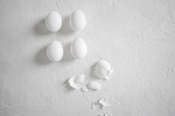 White egg with a shell with flour scattered on a turn with a whisk and a knife and a baking powder for flour on a cement background