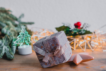 Holiday card with new year decoration, fir tree branches and gift box on white and wooden background.