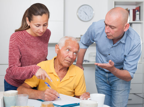 Mature Father And Adult Children Fill Out Paperwork