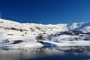Fototapeta na wymiar A lake near a hill covered with snow