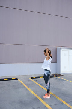 Sportswoman stretching arms against wall.