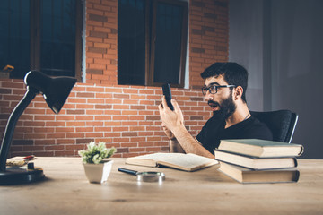 surprised man hand phone with books on desk