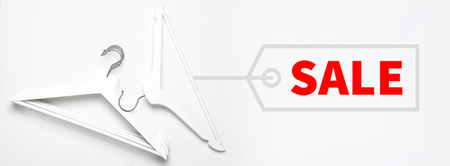 Sale concept. Discount store shopping. Flat lay top view White wooden hangers on white background copy space minimalism style, design empty hanger. Creative fashion background, feminine blog