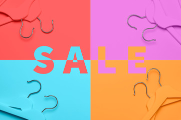 Sale concept. Discount store shopping. Creative fashion concept. Flat lay top view colored wooden hangers on blue pink orange neon background minimalism style pop-art design empty hanger feminine blog