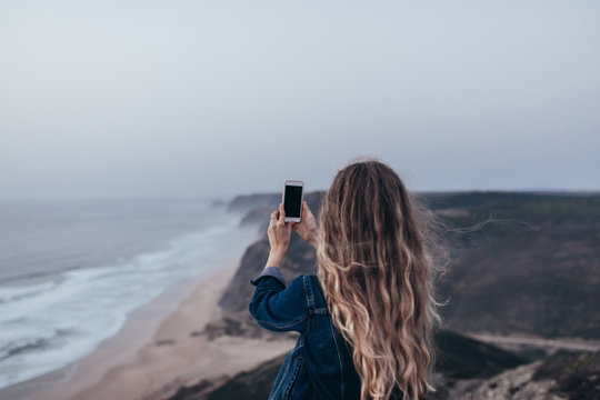 Woman doing pictures with her phone at coast