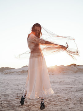 Model in veil dancing in?desert