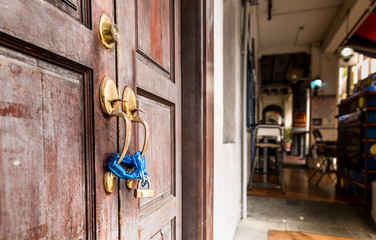 A close up of a blue locked padlock on an old wooden door with no keys to keep thieves away and reduce the risk of theft or intruders breaking into the property by increasing security
