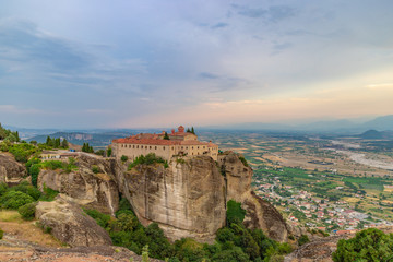 Fototapeta na wymiar Agios Stephanos or Saint Stephen monastery located on the huge rock with mountains and town landscape in the background at evening. Meteors, Trikala, Thessaly, Greece