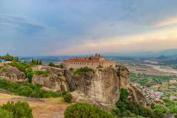 Fototapeta na wymiar Agios Stephanos or Saint Stephen monastery located on the huge rock with mountains and town landscape in the background at evening. Meteors, Trikala, Thessaly, Greece