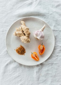 Ginger, garlic and spices on ceramic plate with linen tablecloth