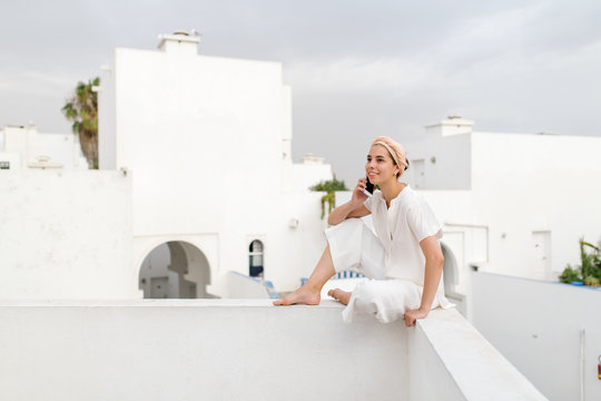 Cheerful woman speaking on phone on border of terrace