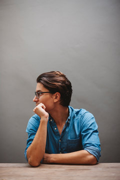 Character man portrait sitting at table against grey wall