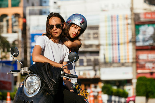 Portrait of young couple sitting on motorbike in city