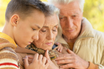 Portrait of sad grandfather, grandmother and grandson hugging