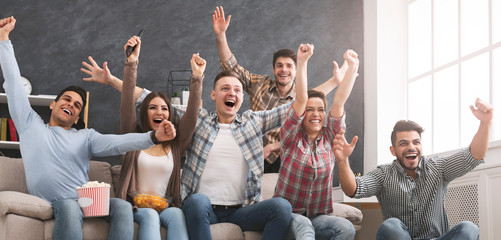 Friends watching football at home and yelling goal