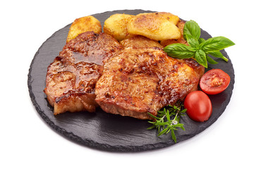 Baked juicy pork steak with fried potatoes on a stone plate, isolated on white background