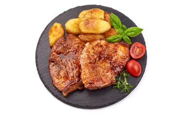 Fried juicy pork steak with potatoes on a stone plate, isolated on white background
