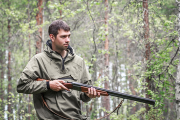 Hunter with shotgun in forest looking out for prey, hunt