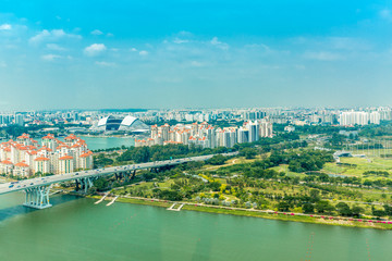 Fototapeta premium Aerial panoramic view over Singapore with the rainforest meeting the city under a clear blue sky