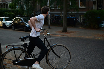 Dutch male student hopping on his bicycle to go for a ride to the city centre