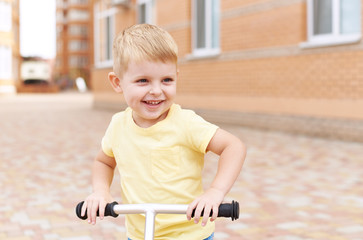 Obraz na płótnie Canvas Cute little boy on bike, bicycle in the yard. Healthy lifestyle of children