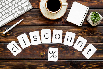 Naklejka premium Sale in shop office with discount word and percent symbol, keyboard, notebook on wooden background top view