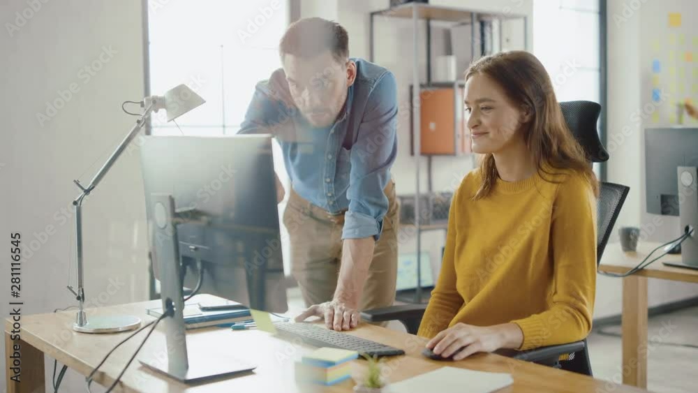 Poster Female Specialist Works on Desktop Computer, Project Manager Stands Beside and gives Advice on Optimizing Workflow for Customer Experience Management. Modern Office with Diverse Team of Professionals