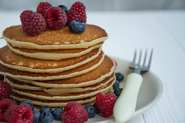 Classic American pancakes with fresh berry on a blue wooden background. Pancakes with fruit. Summer homemade breakfast.