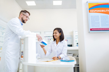 Obraz premium Cheerful dark-skinned woman working in drug store