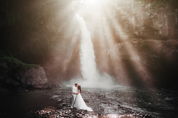 Young couple in love bride and groom, wedding day near a mountain waterfall.