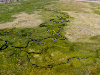 Aerial top view of green land and small curve river in Aspen Springs, Mono County California, USA