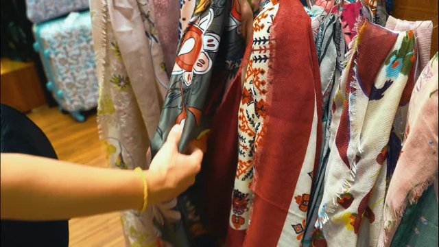 Woman choosing  silk and linen  scarf  at the shop. Variety of colorful  woman' scarfs.
