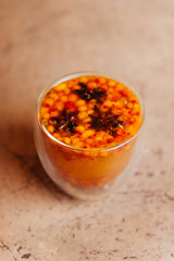 Sea buckthorn tea with orange in a glass cups with fresh sea buckthorn berries and leaves.