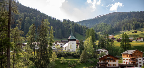 Old church on a wooded mountain at blue sky in the Swiss Alps