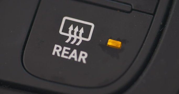 Close up of a finger pushing the rear defogger button in a vehicle